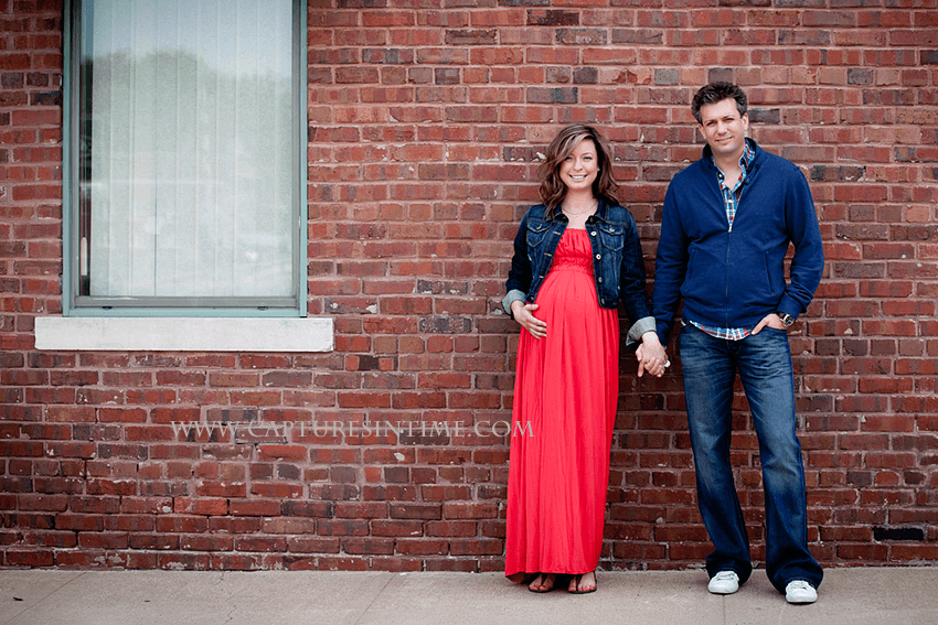 kansas city maternity session mom in red dress holding hands with dad