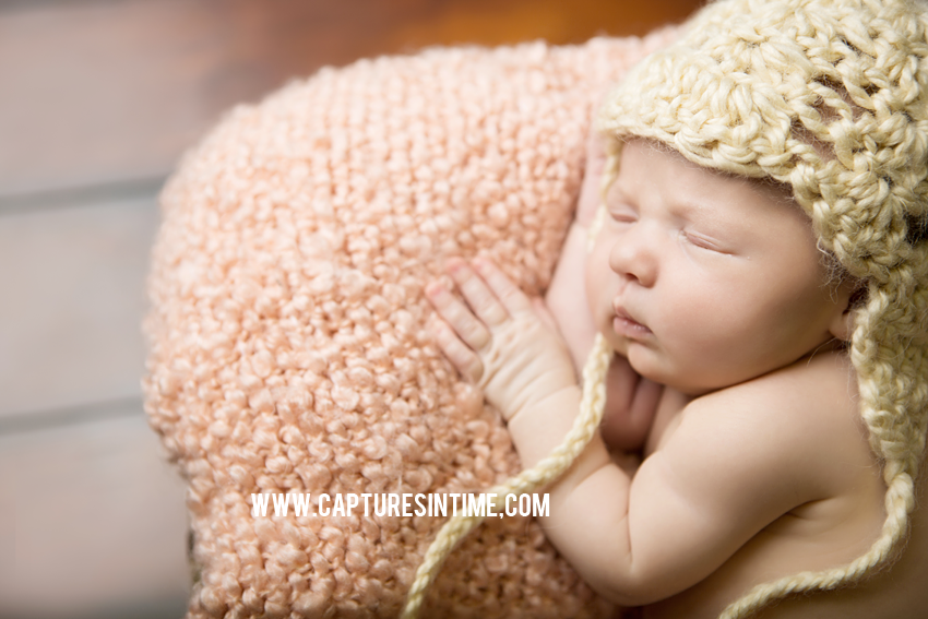 newborn girl with salmon and cream hat
