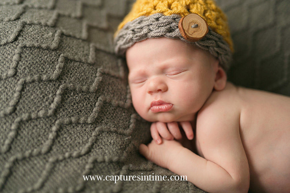 newborn photographer newborn baby boy with yellow and cream hat full lips and hand under his chin