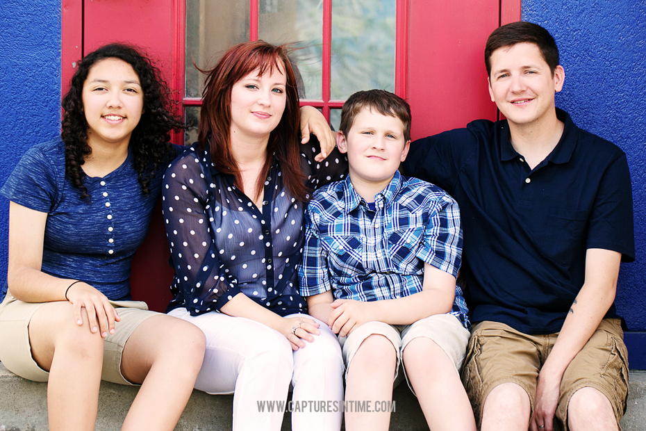family in front of red and blue building
