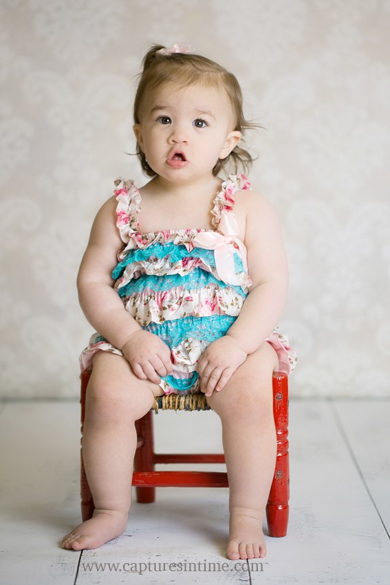baby photographer lees summit toddler in floral romper sitting in chair