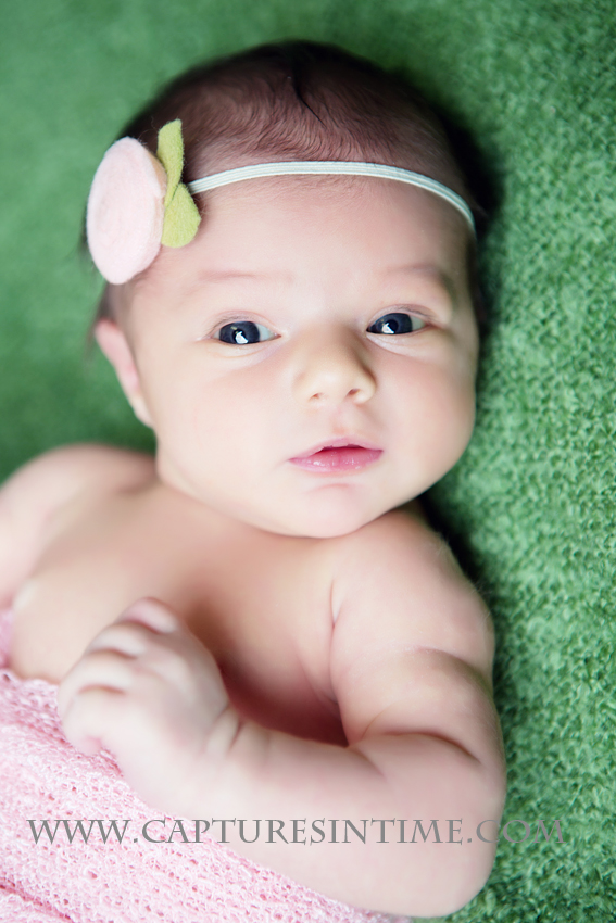 Kansas City Newborn Girl Photos baby girl on green blanket with pink wrap