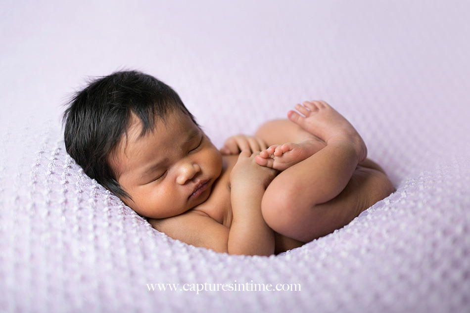 kansas city newborn photographer Mia newborn baby dark hair on lavender blacket in huck finn poset