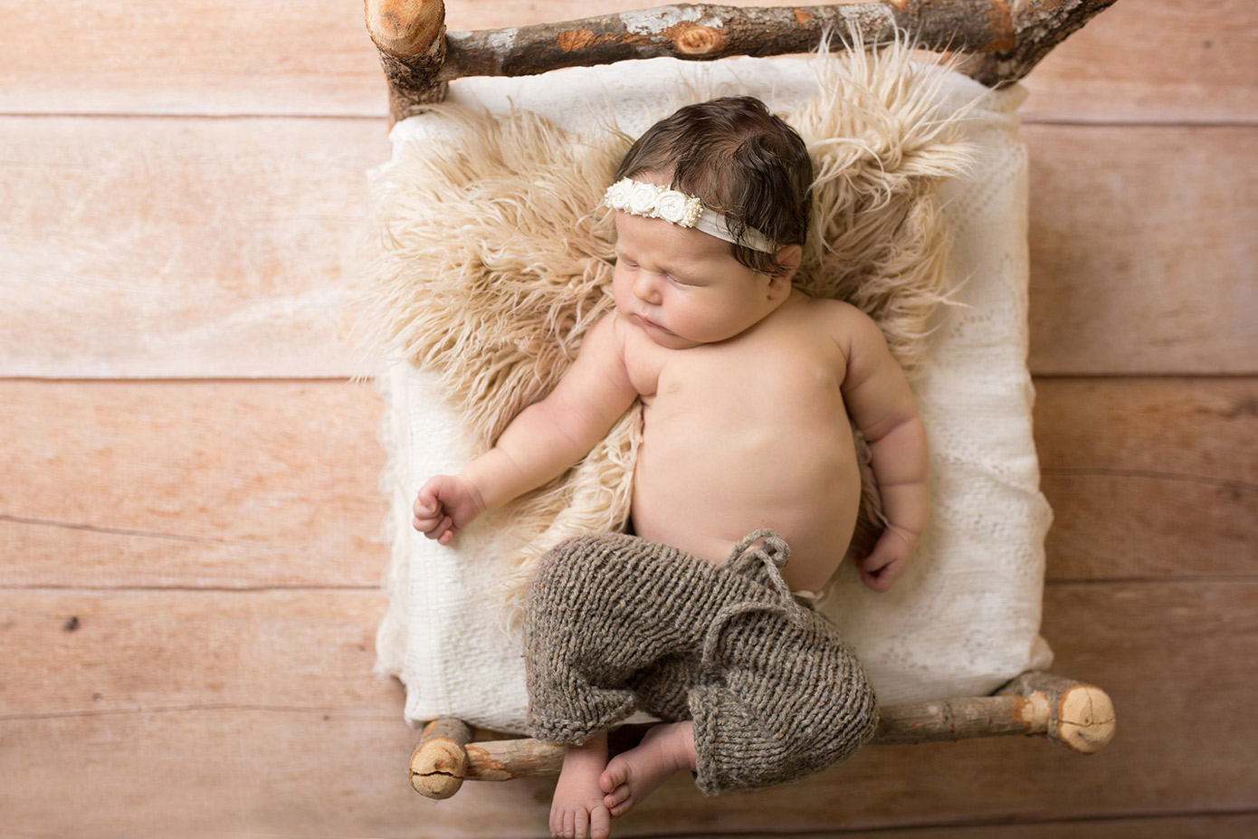 newborn girl in birch bed wood floor