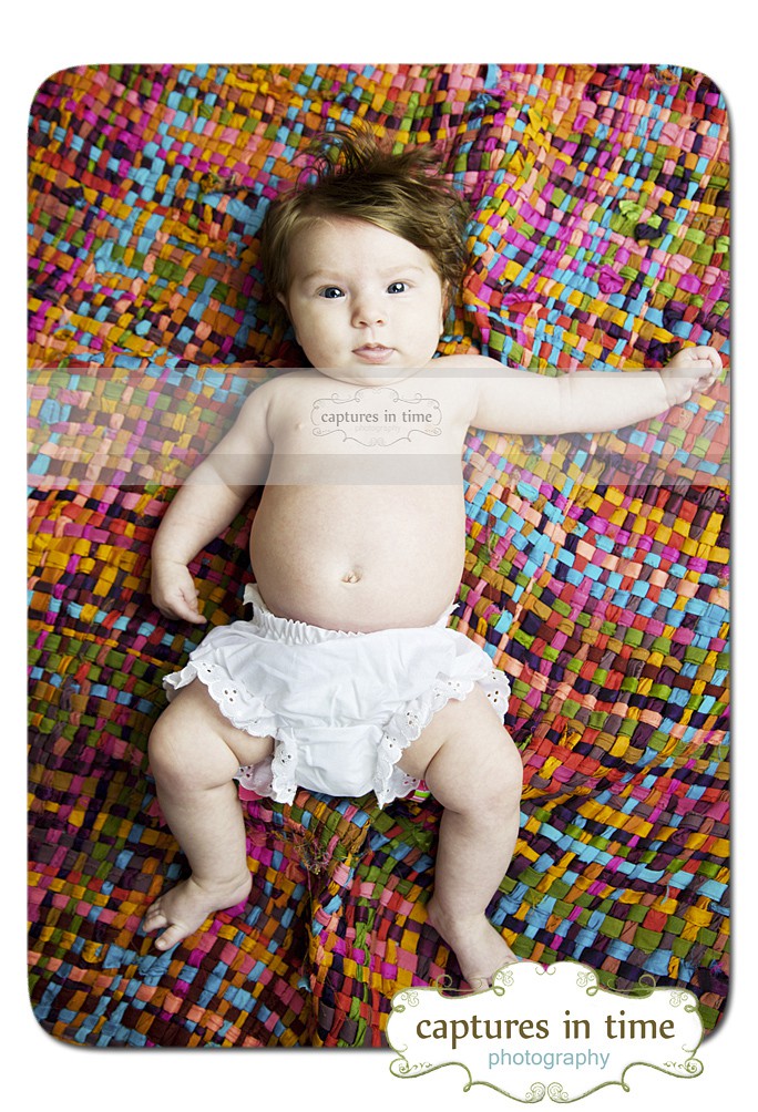 baby in white bloomers on colorful blanket