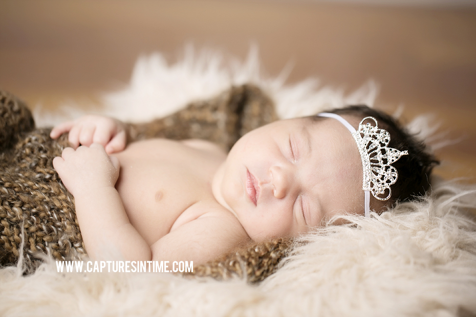 baby sleeping with tiara in brown sack