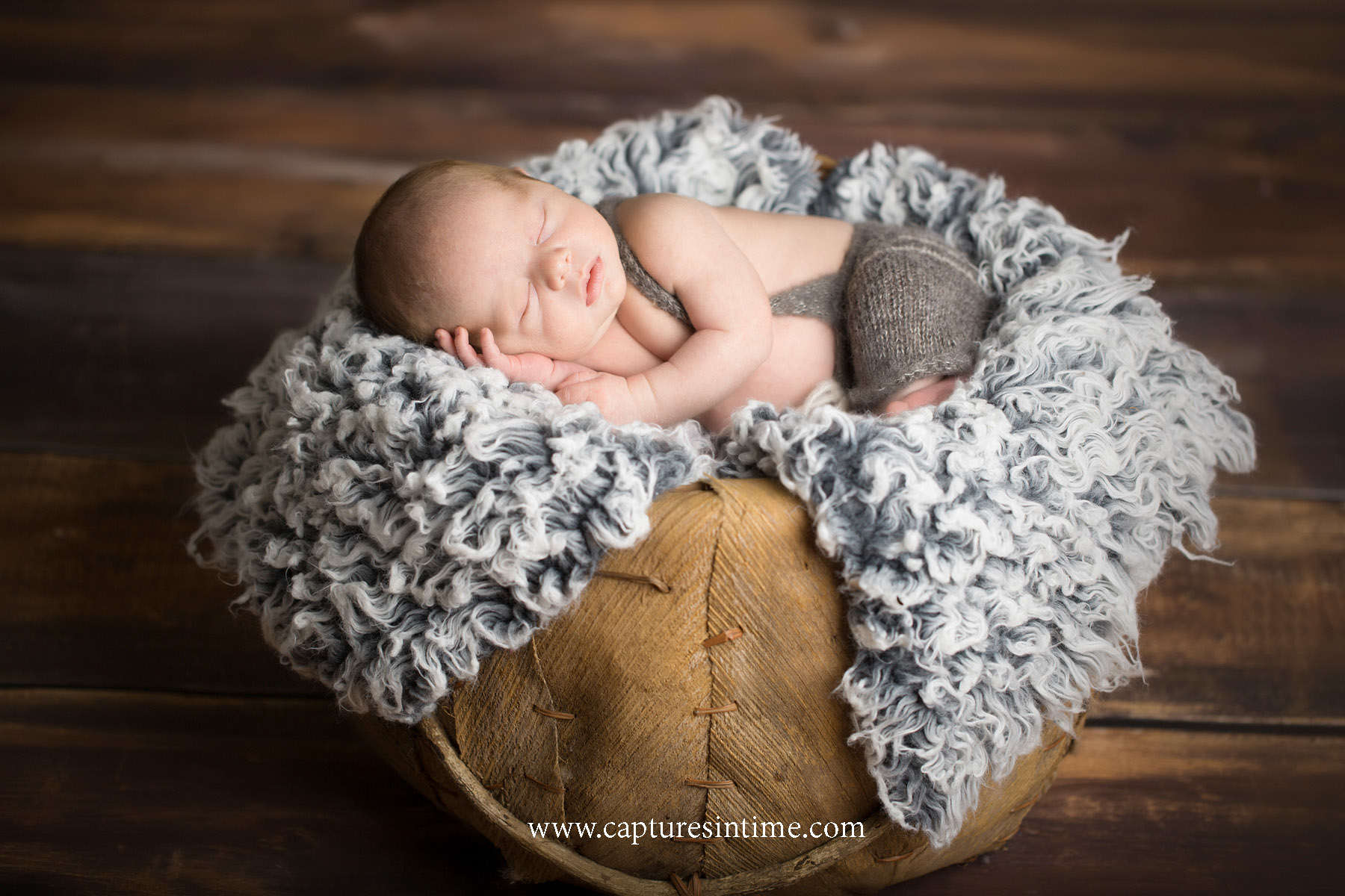 best kansas city newborn photos newborn boy with suspender romper on gray blanket in organic basket