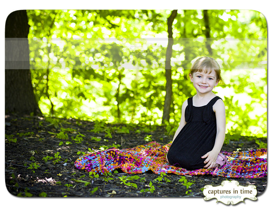girl under tree on colorful blanket
