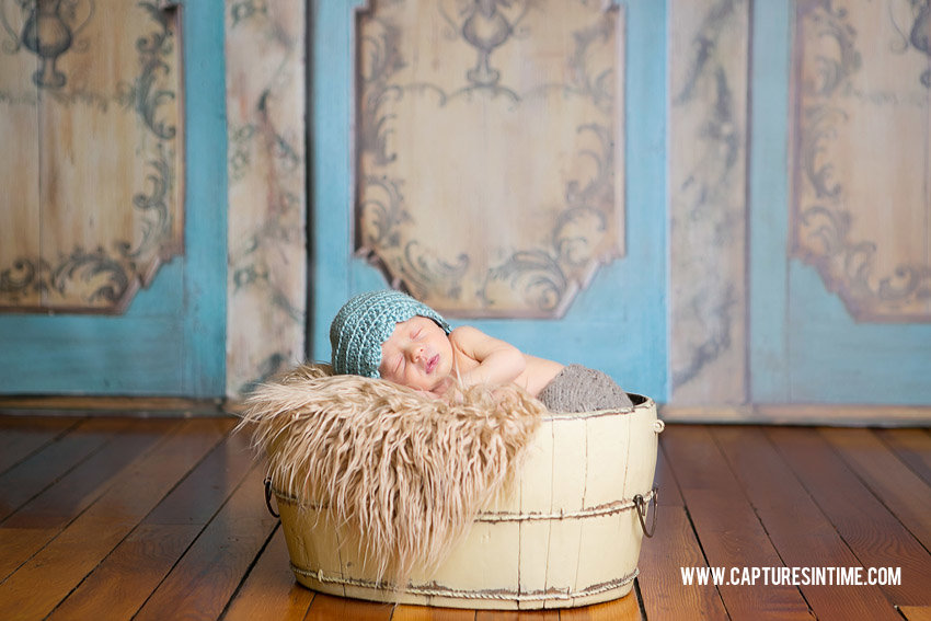 Grain Valley Newborn Photography newborn baby in front of armoire backdrop with teal hat on