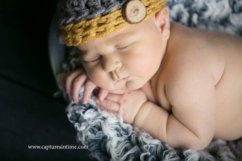 newborn baby boy with rolls wearing yellow and gray hat
