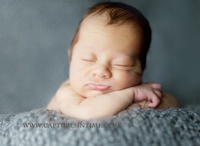 newborn photos on a grey blanket with funny face 