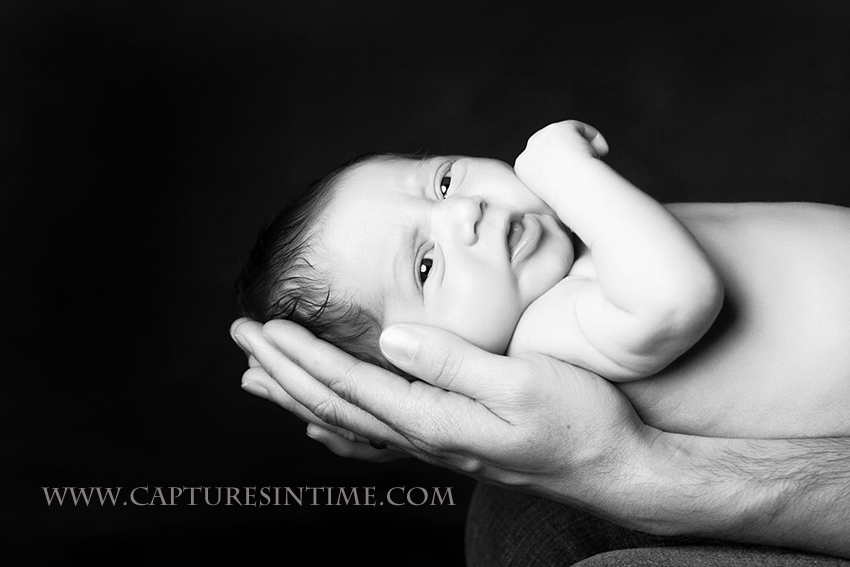 black and white of newborn in dad's hands KC