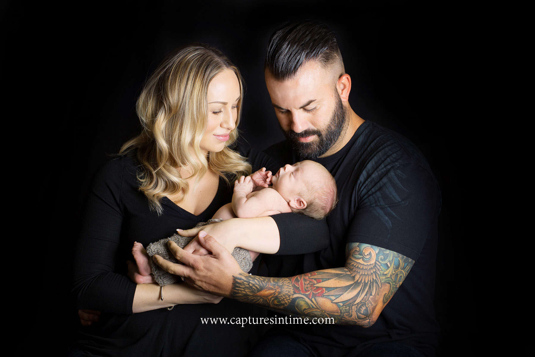 best kansas city newborn photos mom and day wearing all black holding their brand new baby
