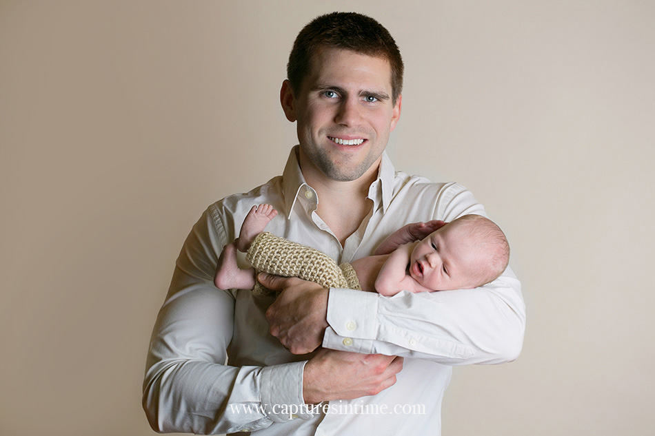 newborn photographer handsome dad in button up shirt holding his new baby boy