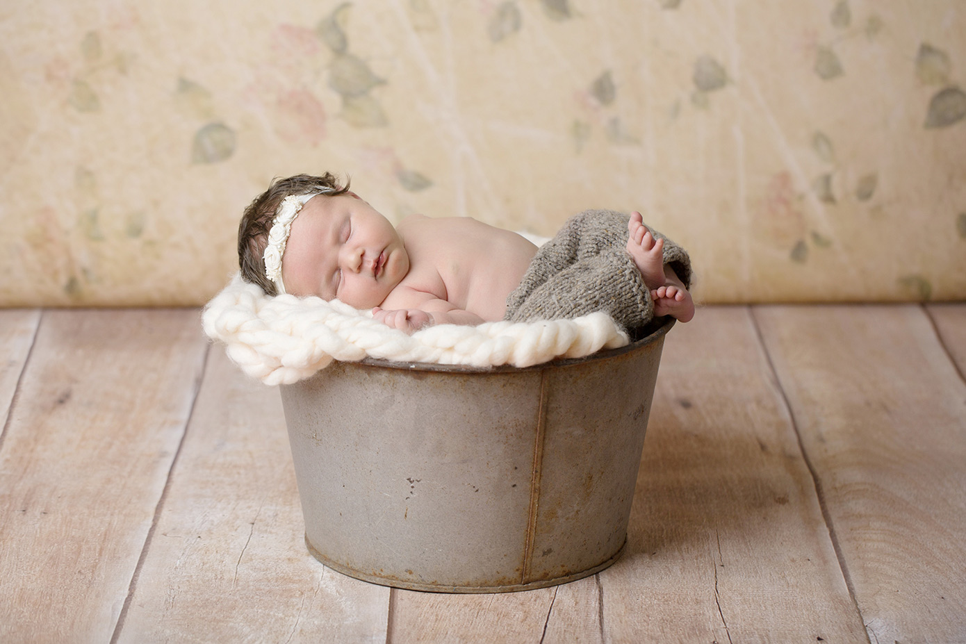 newborn girl in metal bucket floral backdrop