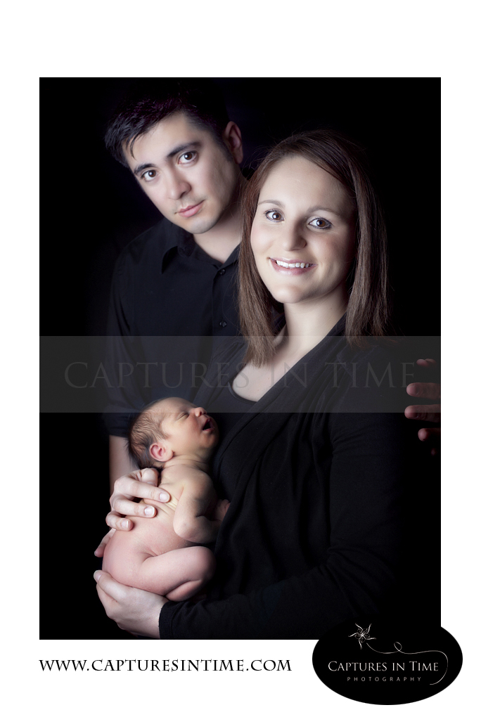 Kansas City Newborn Photographer mom holding preemie with dad on black backdrop