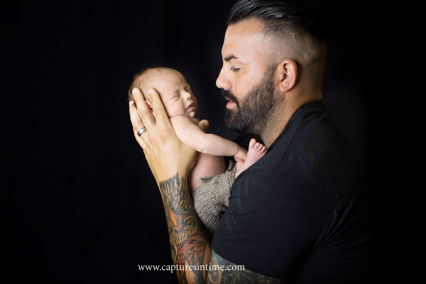 best kansas city newborn photos dad with tattoo sleeve and beard hold his newborn baby